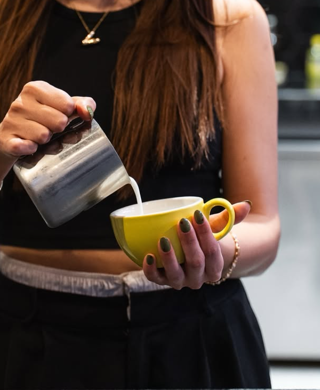 Barista de Petros sirviendo leche